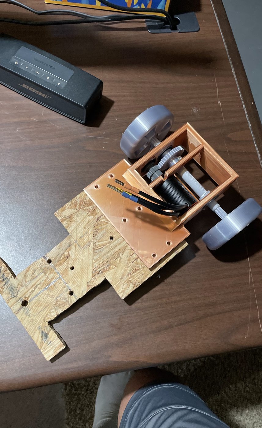 Mid-build RC car chassis with the printed gearbox on a plywood base